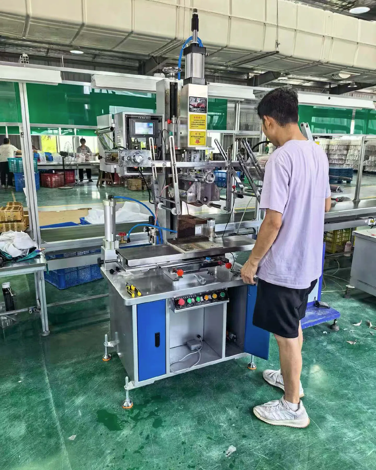 Operator checking a manual semi-automatic hot stamping machine in a workshop